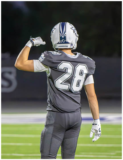 A football player wearing a blue and white uniform. Description generated by AI
