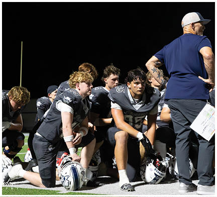 A group of football players huddled together on the field. Description generated by AI