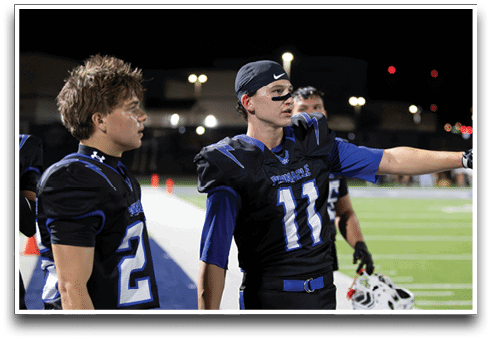 Three football players are standing on the field, one of them is smiling and wearing a black jersey with the number 55. AI generated content