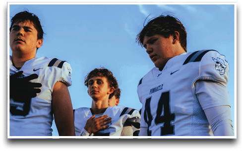 Three football players are standing on the field, one of them is smiling and wearing a black jersey with the number 55. AI generated content