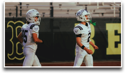 Three football players are standing on the field, one of them is smiling and wearing a black jersey with the number 55. AI generated content