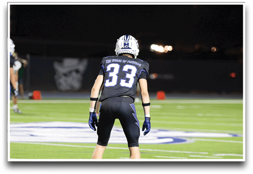 Three football players are standing on the field, one of them is smiling and wearing a black jersey with the number 55. AI generated content