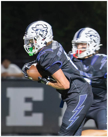 A football player wearing a blue and white uniform. Description generated by AI