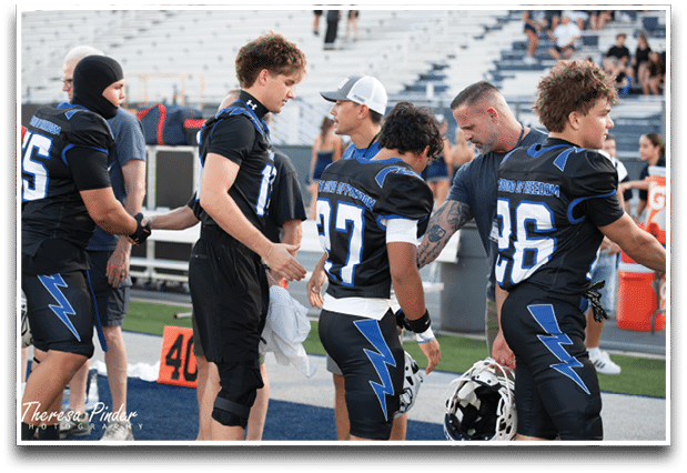 Three football players are standing on the field, one of them is smiling and wearing a black jersey with the number 55. AI generated content
