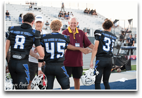 Three football players are standing on the field, one of them is smiling and wearing a black jersey with the number 55. AI generated content
