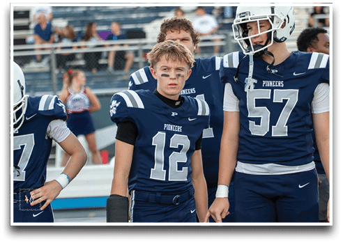 Three football players are standing on the field, one of them is smiling and wearing a black jersey with the number 55. AI generated content
