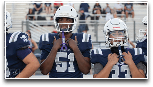 Three football players are standing on the field, one of them is smiling and wearing a black jersey with the number 55. AI generated content