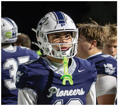 A group of football players huddled together on the field. Description generated by AI