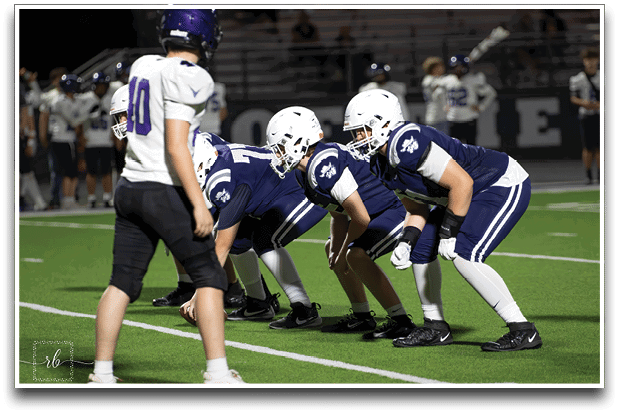 Three football players are standing on the field, one of them is smiling and wearing a black jersey with the number 55. AI generated content