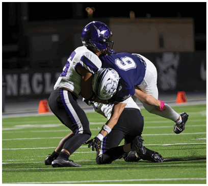 A group of football players huddled together on the field. Description generated by AI