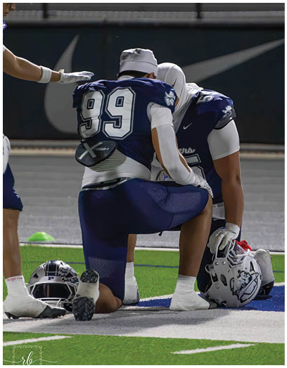 A football player wearing a blue and white uniform. Description generated by AI
