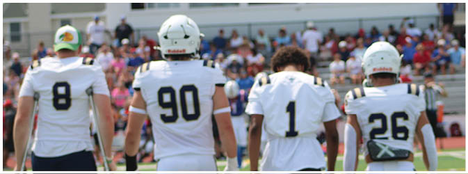 A football game is taking place on a field with players wearing blue and white uniforms. Description generated by AI