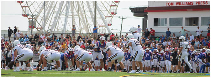A football game is taking place on a field with players wearing blue and white uniforms. Description generated by AI