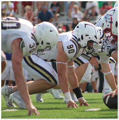 A football game is taking place with a group of men on the field. Description generated by AI