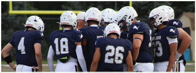 A football game is taking place on a field with players wearing blue and white uniforms. Description generated by AI