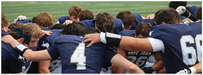 A football game is taking place on a field with players wearing blue and white uniforms. Description generated by AI