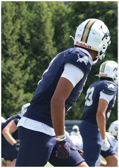 A football player wearing a blue and red jersey. Description generated by AI
