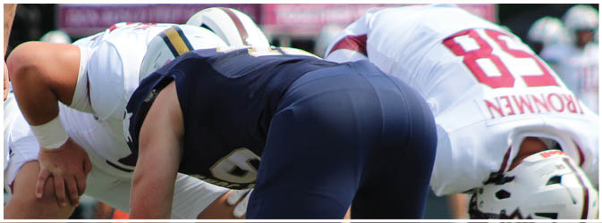 A football game is taking place on a field with players wearing blue and white uniforms. Description generated by AI