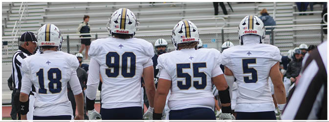 A football game is taking place on a field with players wearing blue and white uniforms. Description generated by AI