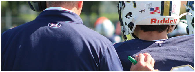A football game is taking place on a field with players wearing blue and white uniforms. Description generated by AI