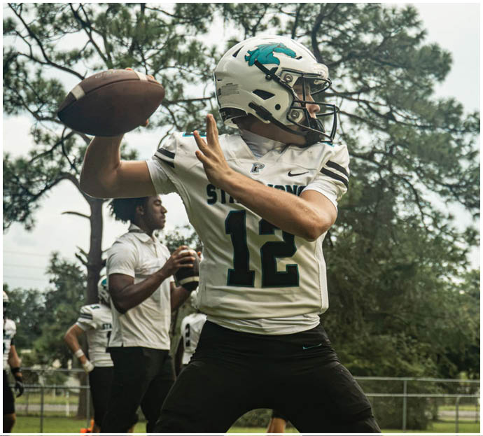 Three football players in blue and white uniforms running on a field. Description generated by AI