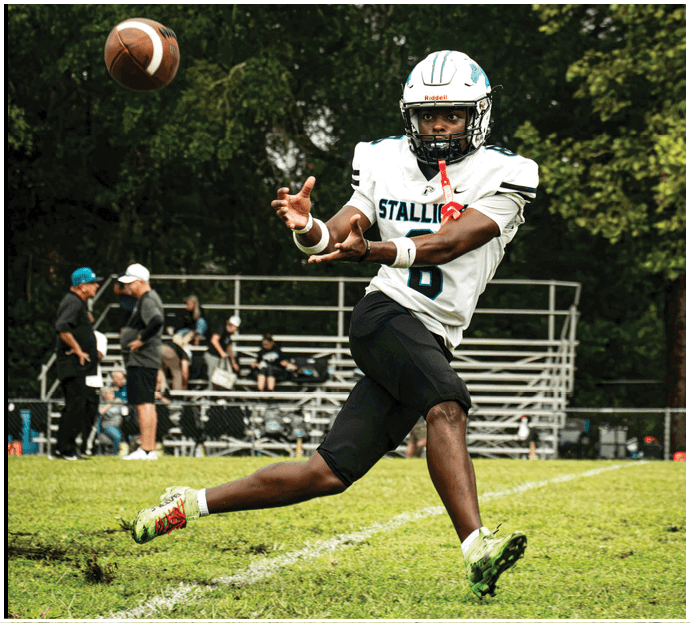 Three football players in blue and white uniforms running on a field. Description generated by AI
