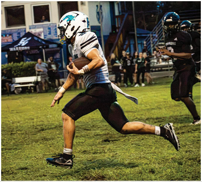 Three football players in blue and white uniforms running on a field. Description generated by AI