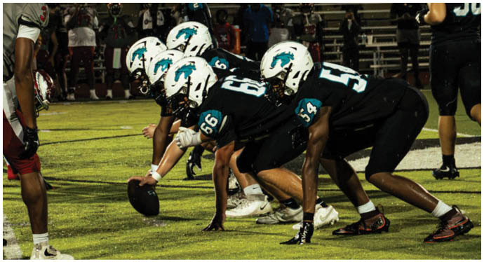 A group of football players on a field. Description generated by AI