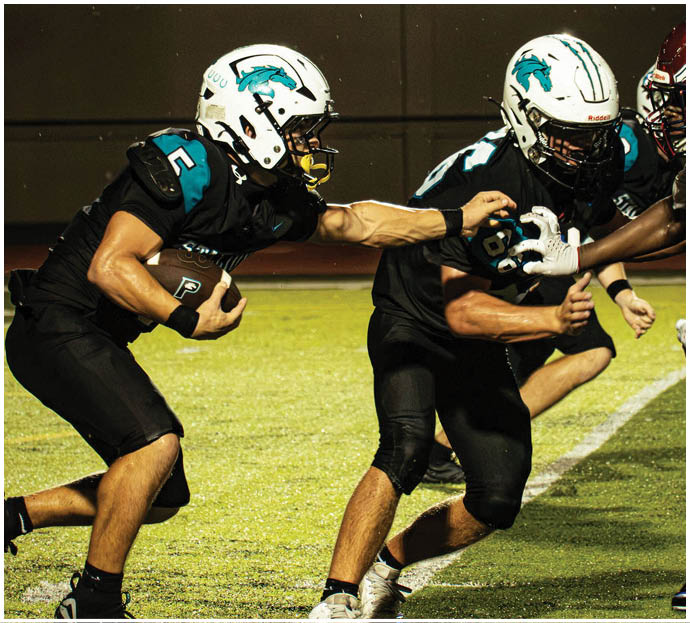 Three football players in blue and white uniforms running on a field. Description generated by AI