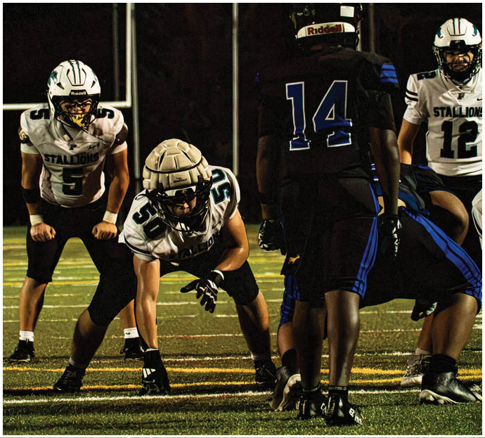 Three football players in blue and white uniforms running on a field. Description generated by AI