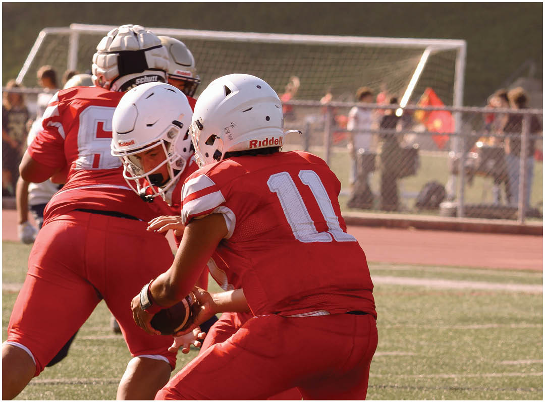 Three football players in blue and white uniforms running on a field. Description generated by AI