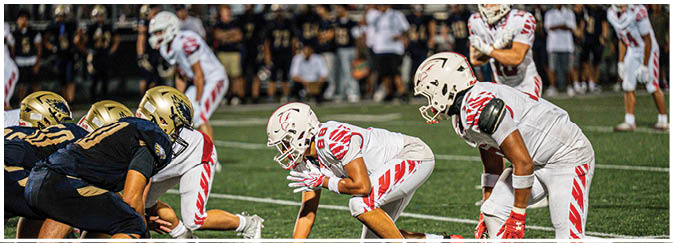 A football game is taking place on a field with players wearing blue and white uniforms. Description generated by AI