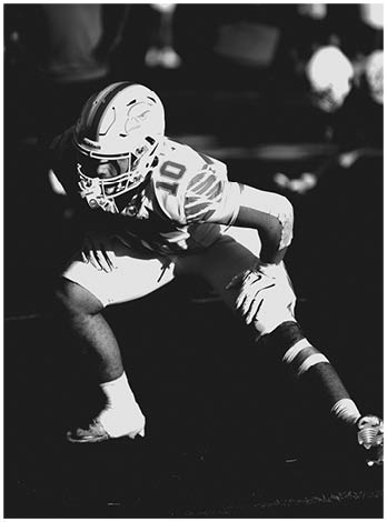 A football player wearing a blue and red jersey. Description generated by AI