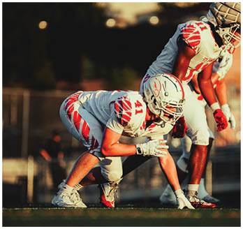 A football game is taking place with a group of men on the field. Description generated by AI