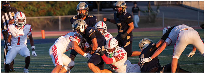 A football game is taking place on a field with players wearing blue and white uniforms. Description generated by AI