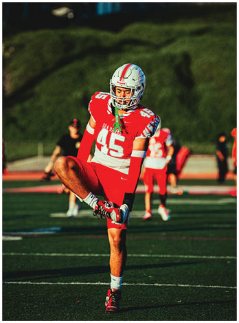 A football player wearing a blue and red jersey. Description generated by AI