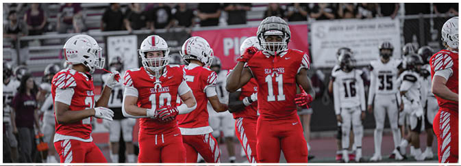 A football game is taking place on a field with players wearing blue and white uniforms. Description generated by AI
