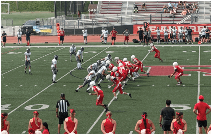 Three football players in blue and white uniforms running on a field. Description generated by AI
