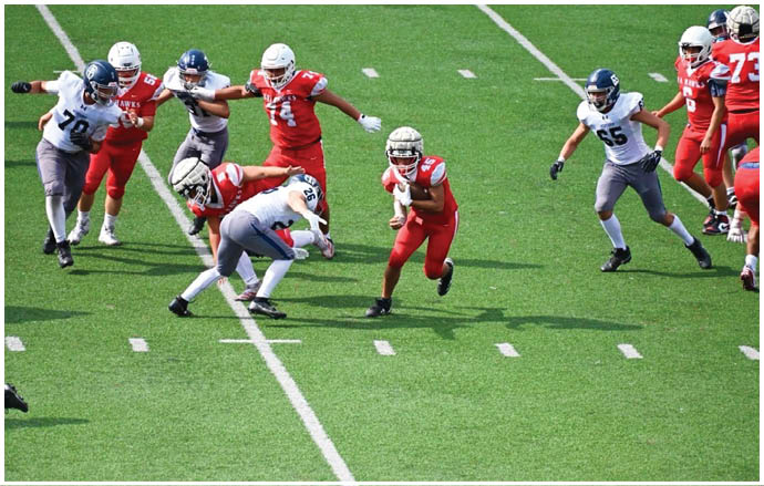 Three football players in blue and white uniforms running on a field. Description generated by AI