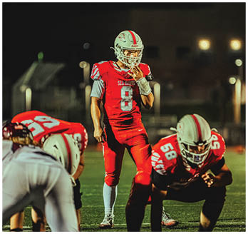 A football game is taking place with a group of men on the field. Description generated by AI