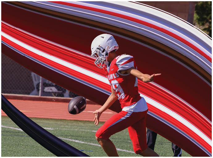 Three football players in blue and white uniforms running on a field. Description generated by AI