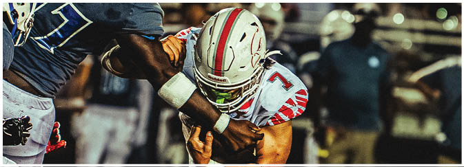 A football game is taking place on a field with players wearing blue and white uniforms. Description generated by AI