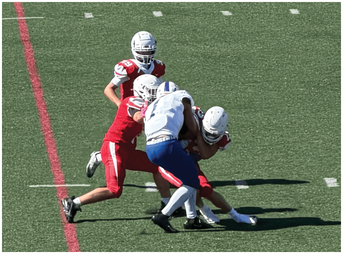 Three football players in blue and white uniforms running on a field. Description generated by AI