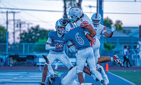 Two men wearing football uniforms are hugging each other on a field. AI generated content