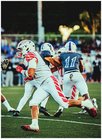 A football player wearing a blue and red jersey. Description generated by AI