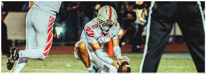 A football game is taking place on a field with players wearing blue and white uniforms. Description generated by AI