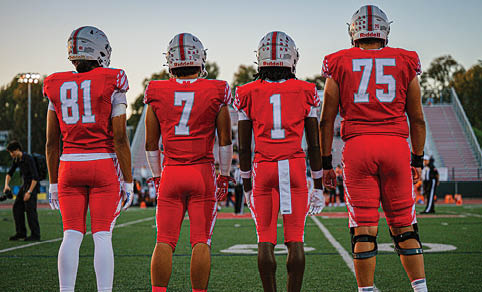 Two men wearing football uniforms are hugging each other on a field. AI generated content