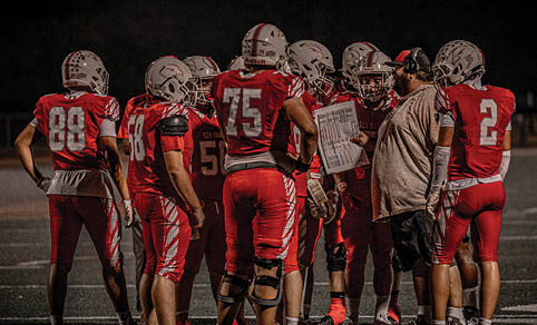 Two men wearing football uniforms are hugging each other on a field. AI generated content