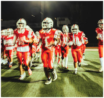 A football game is taking place with a group of men on the field. Description generated by AI
