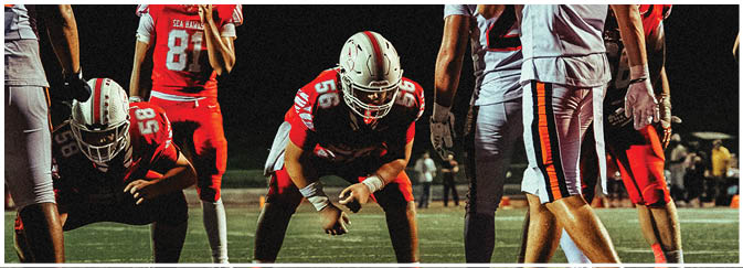 A football game is taking place on a field with players wearing blue and white uniforms. Description generated by AI